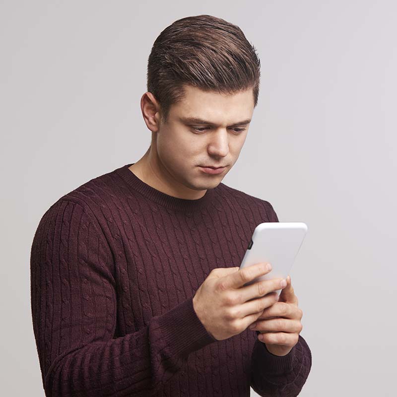 portrait of a young white man using a smartphone PBFJNAY